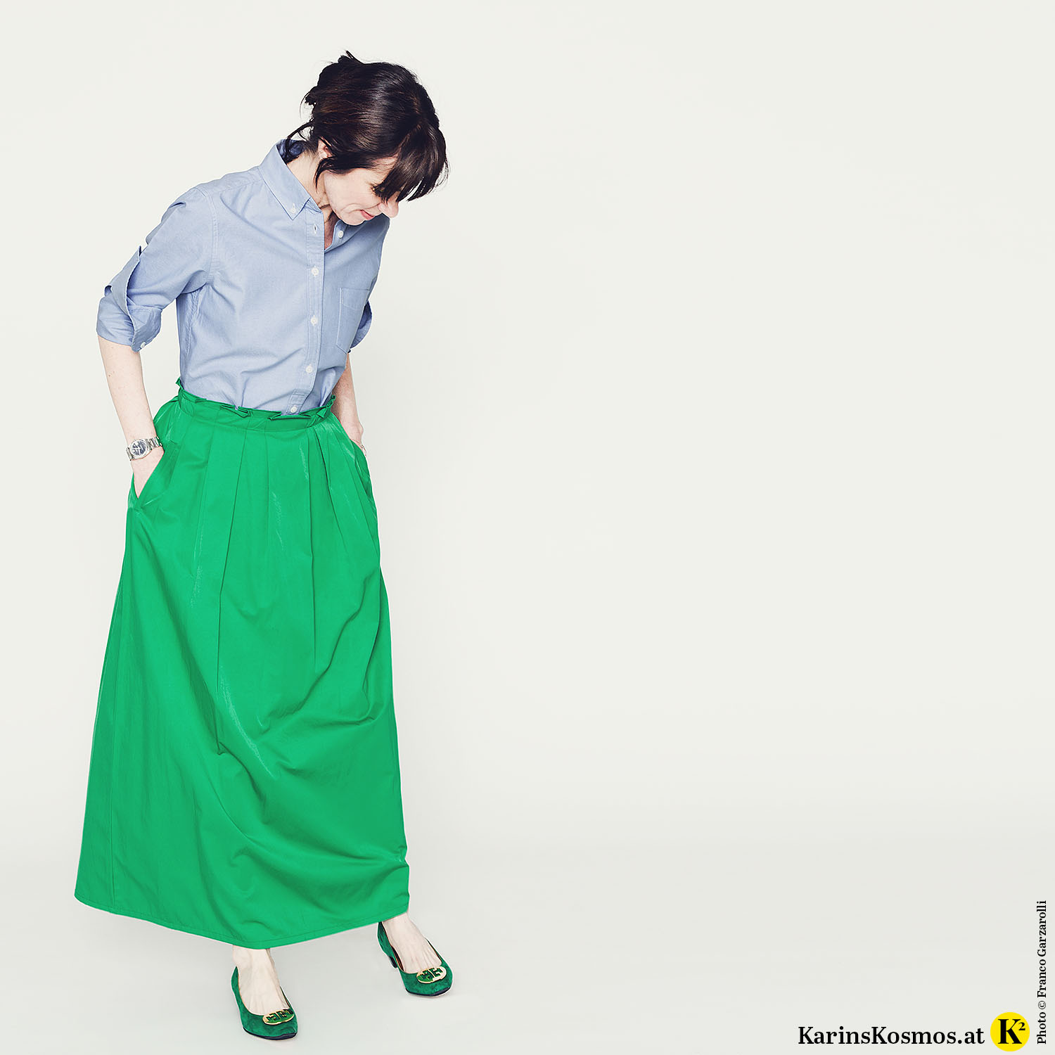 Frau in blauem Hemd mit grünem Rock und grünen Ballerinas.