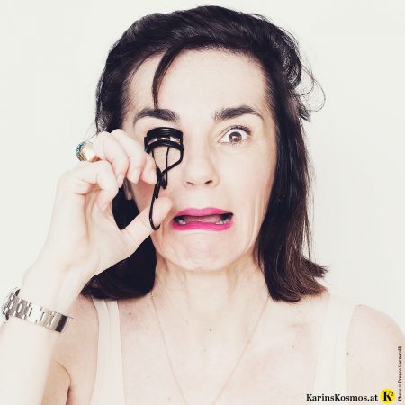 Frau mit leichten Tagesmake-up und einer Wimpernzange.