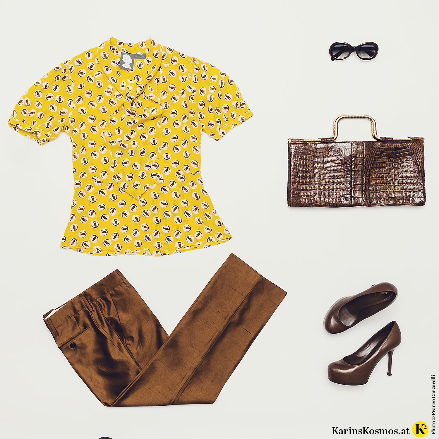 Produktfoto mit gelber Seidenbluse, brauner Seidenhose und Sonnenbrille, Abendtasche und Pumps in Braun.