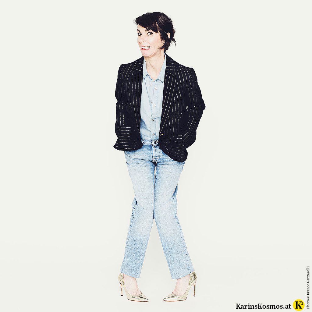 Frau in den Wechseljahren in Jeanshemd und Jeans mit dunklem Blazer.