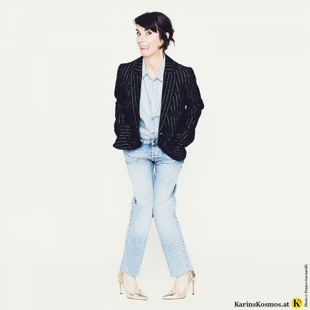 Frau in den Wechseljahren in Jeanshemd und Jeans mit dunklem Blazer.