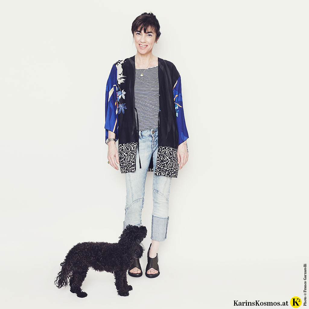 Foto mit Frau in Kimono zu Jeans und T-Shirt, davor steht ein schwarzer Toypudel.