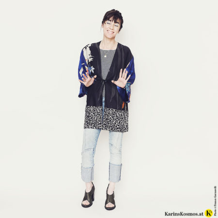 Frau mit einem Kimono, Streifen-Shirt, Jeans und Sandalen.