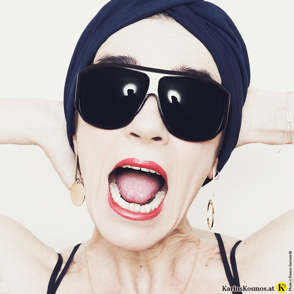 Portrait einer Frau mit Sonnenbrille und Turban im Haar.