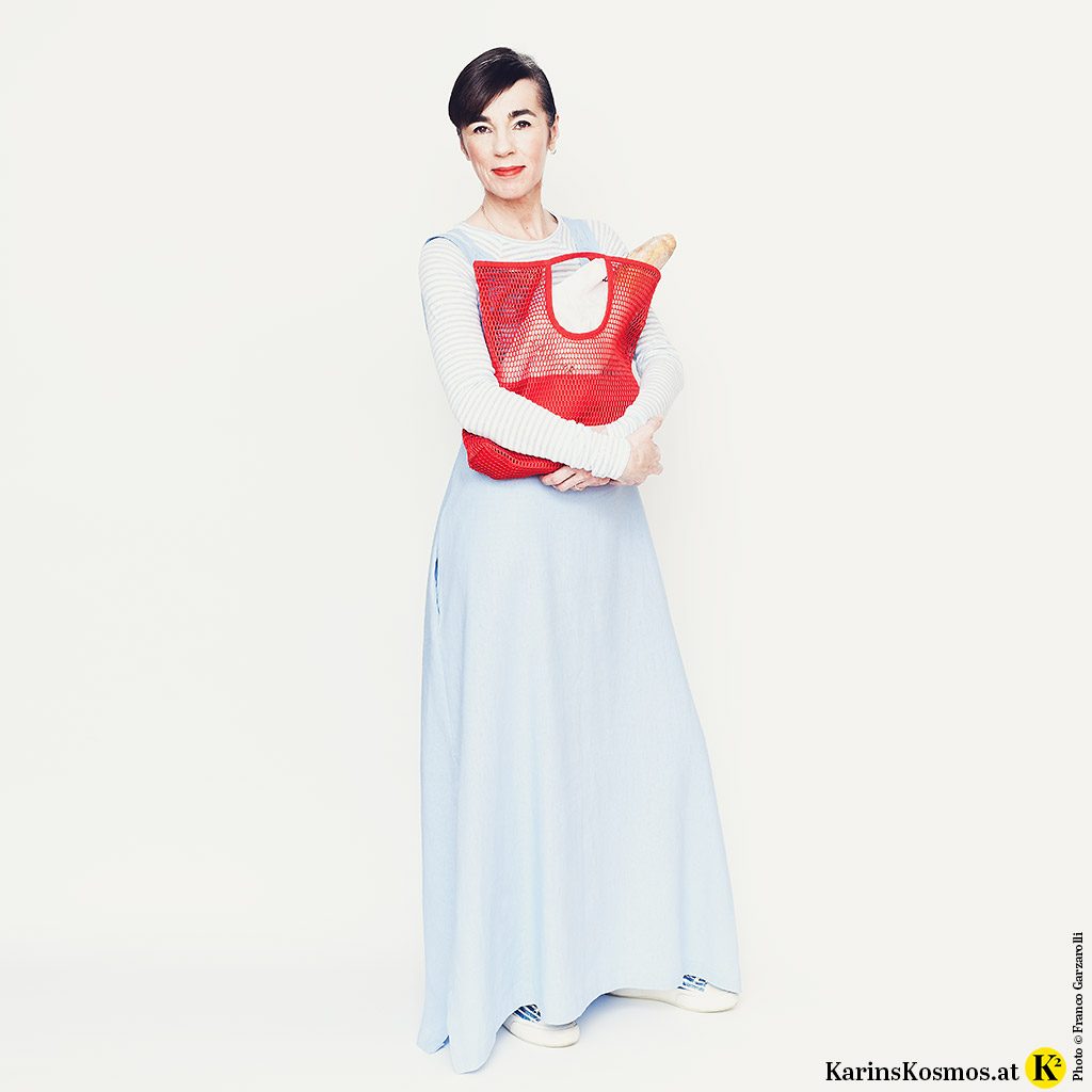 Frau in Leinenkleid für den Sommer mit Einkaufstasche und Sneakers.