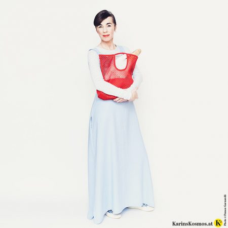 Frau in Leinenkleid für den Sommer mit Einkaufstasche und Sneakers.