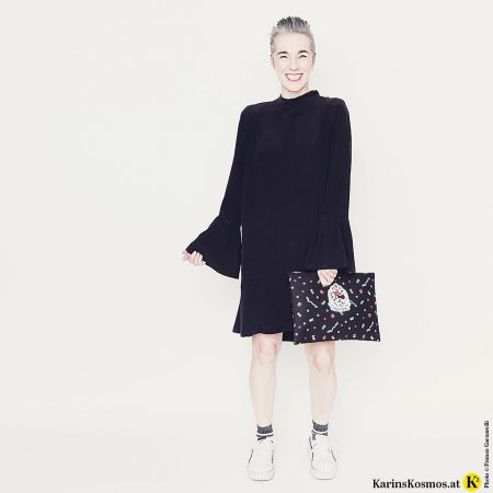 Eine Frau trägt das kleine Schwarze aus Seide mit Turnschuhen dazu.