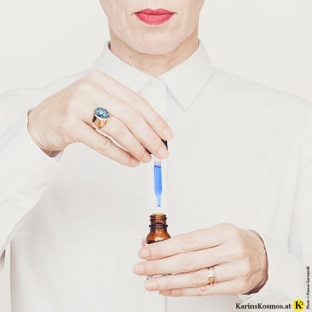 Frau in weißer Bluse, die gerade dabei ist, Pflege-Seren zu testen.